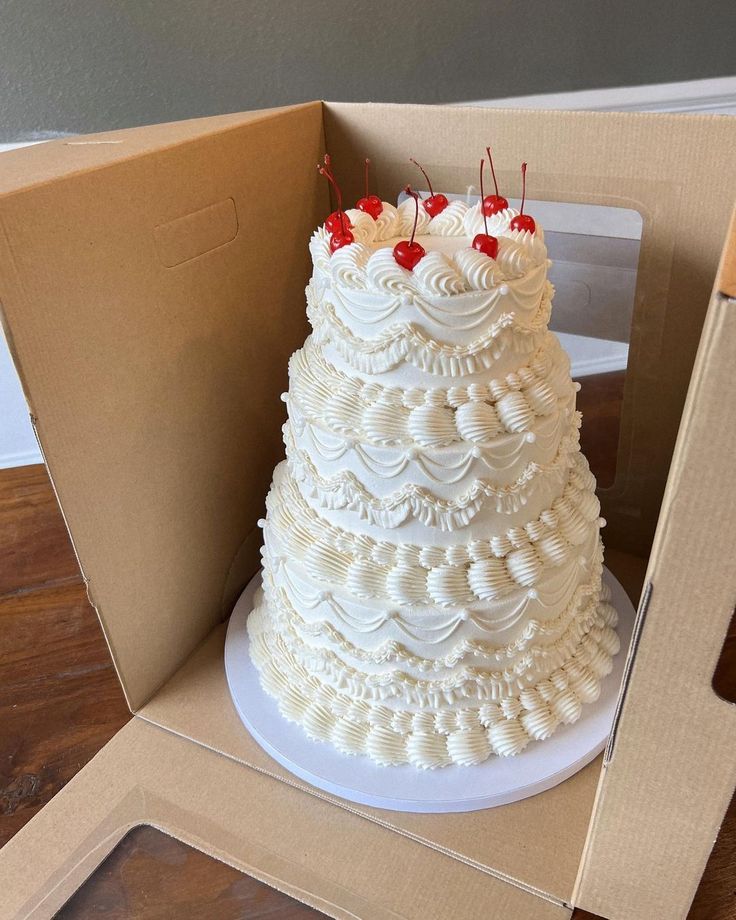 a large white cake sitting inside of a box on top of a wooden floor next to a cardboard box