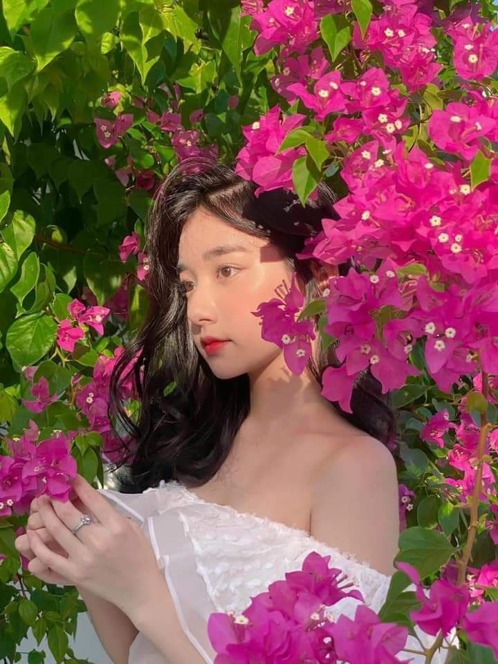 a woman in white dress surrounded by pink flowers