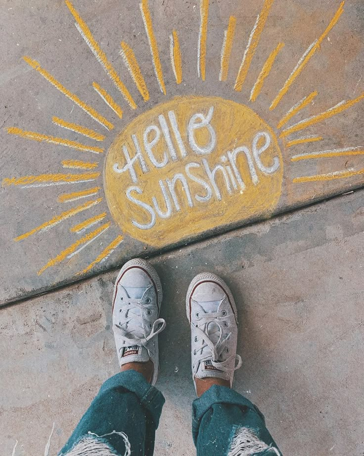 someone is standing on the sidewalk with their feet up in front of them and writing hello sunshine