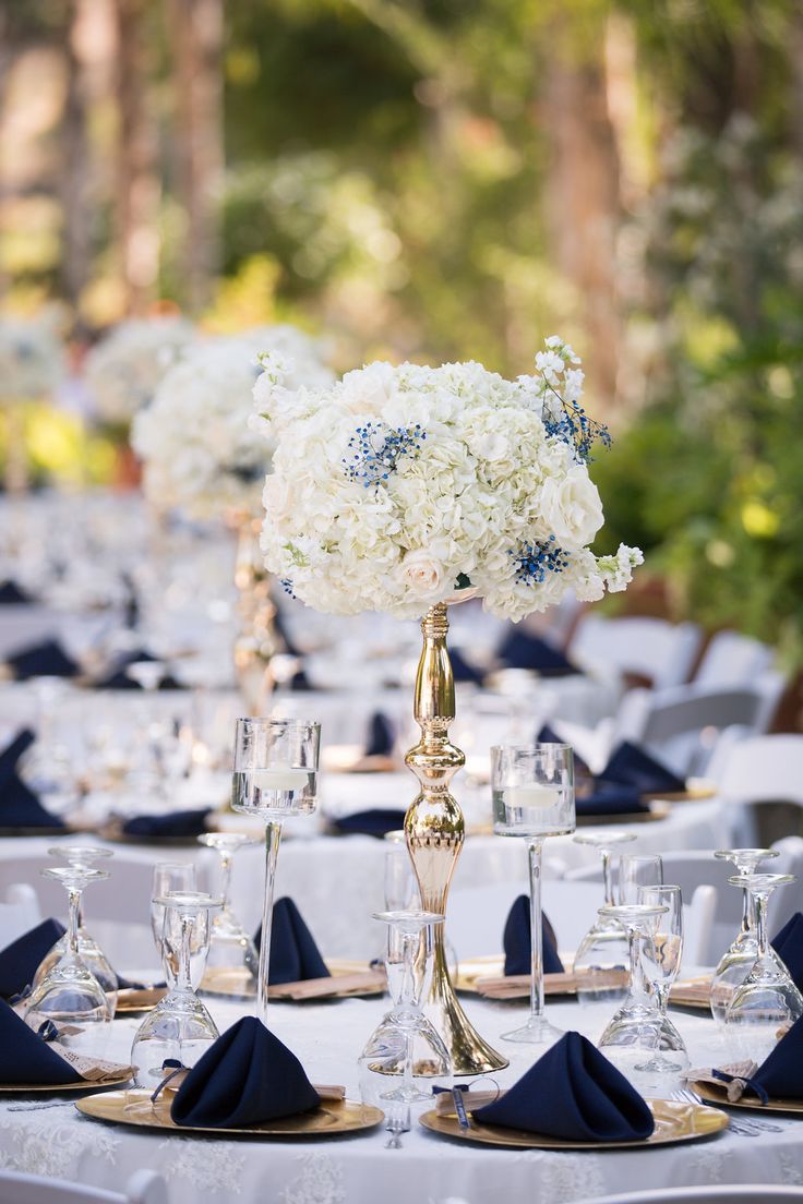 the centerpieces on this table are filled with white and blue flowers