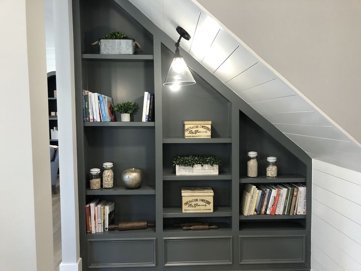 a book shelf with books and other items under a slanted wall in an attic