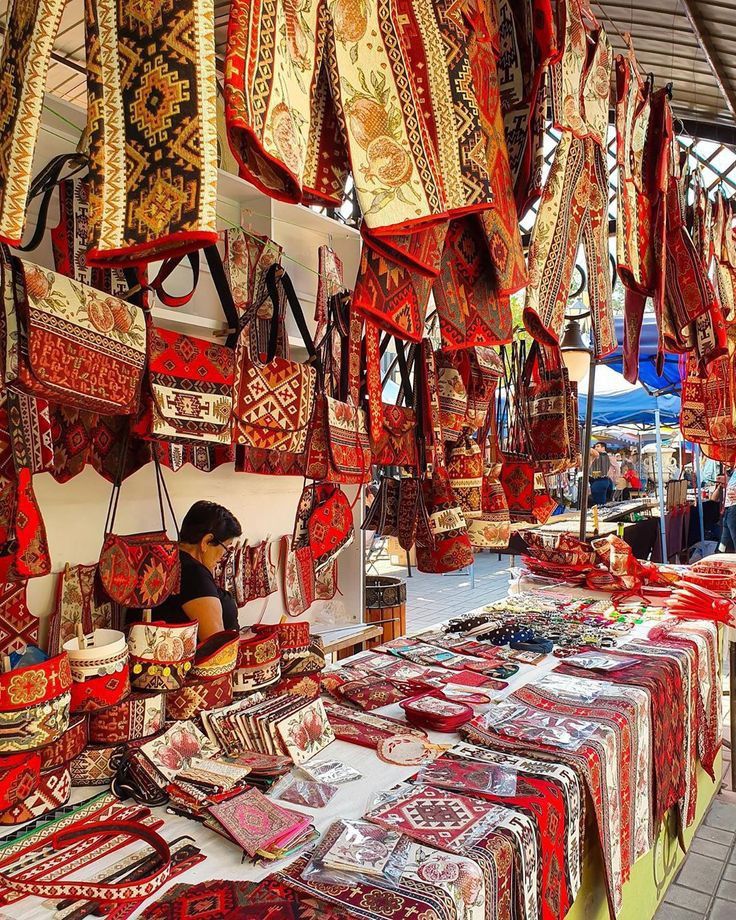 an outdoor market with lots of red and white cloths hanging from it's ceiling