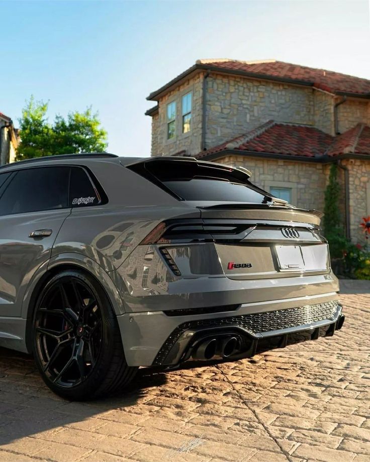 an suv parked in front of a house on a cobblestone street with a brick driveway