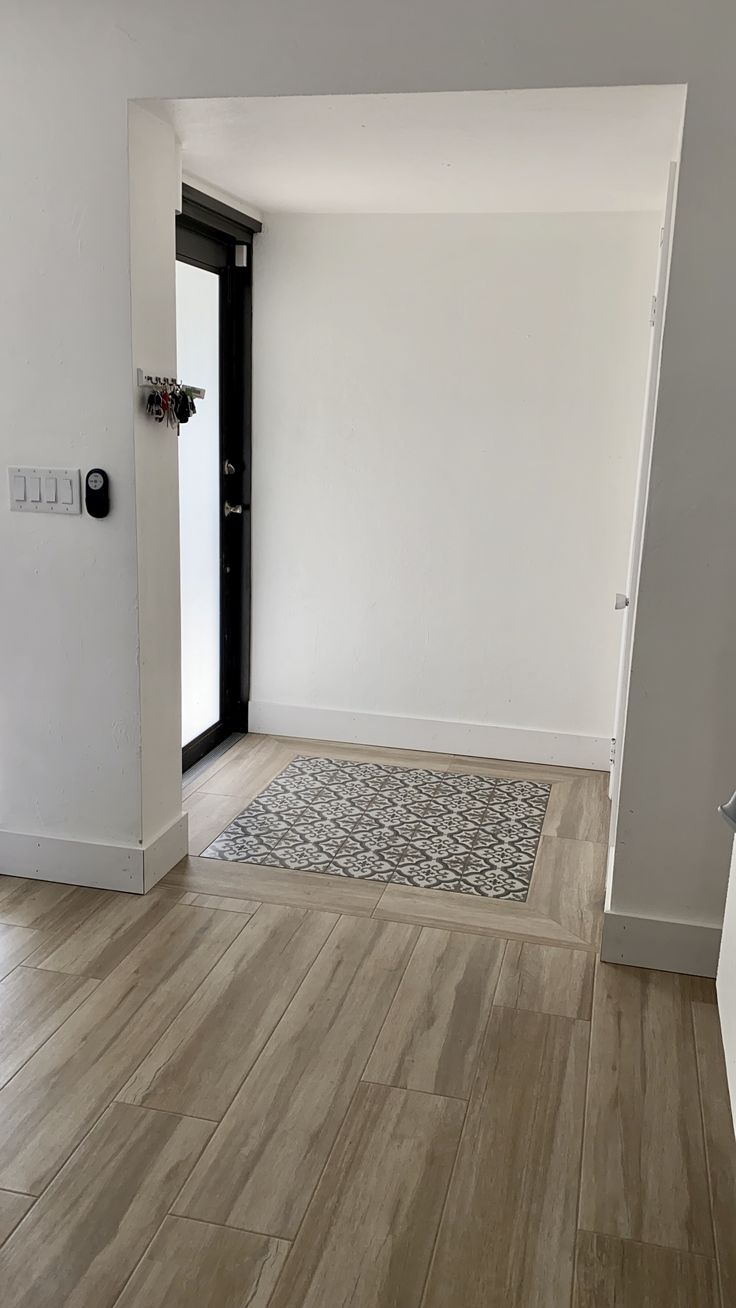 an empty room with wood flooring and white walls is seen in this image from the doorway