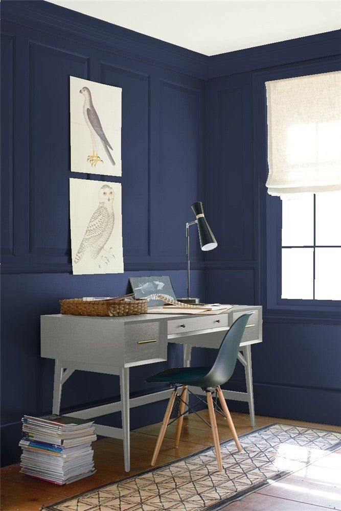 a room with green walls and a desk in front of a window that has two pictures on the wall