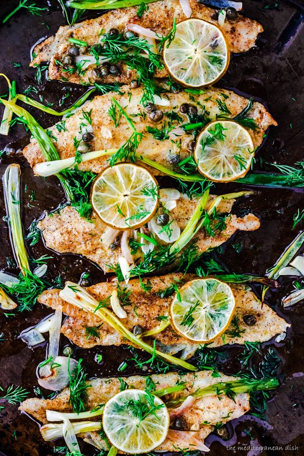 chicken with lemons, onions and herbs on a baking sheet