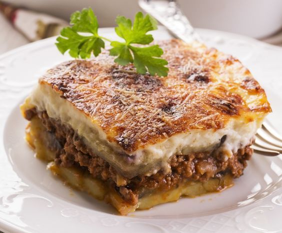 a white plate topped with lasagna covered in sauce and cheese next to a fork