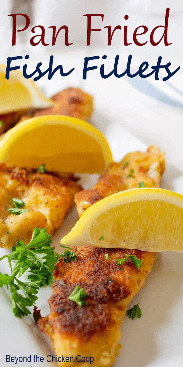 a white plate topped with fish fillets and lemon wedges