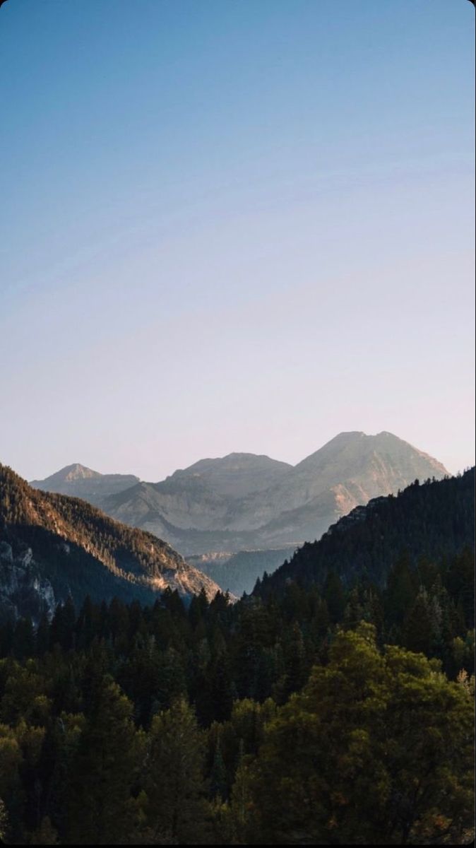 mountains with trees in the foreground and blue sky