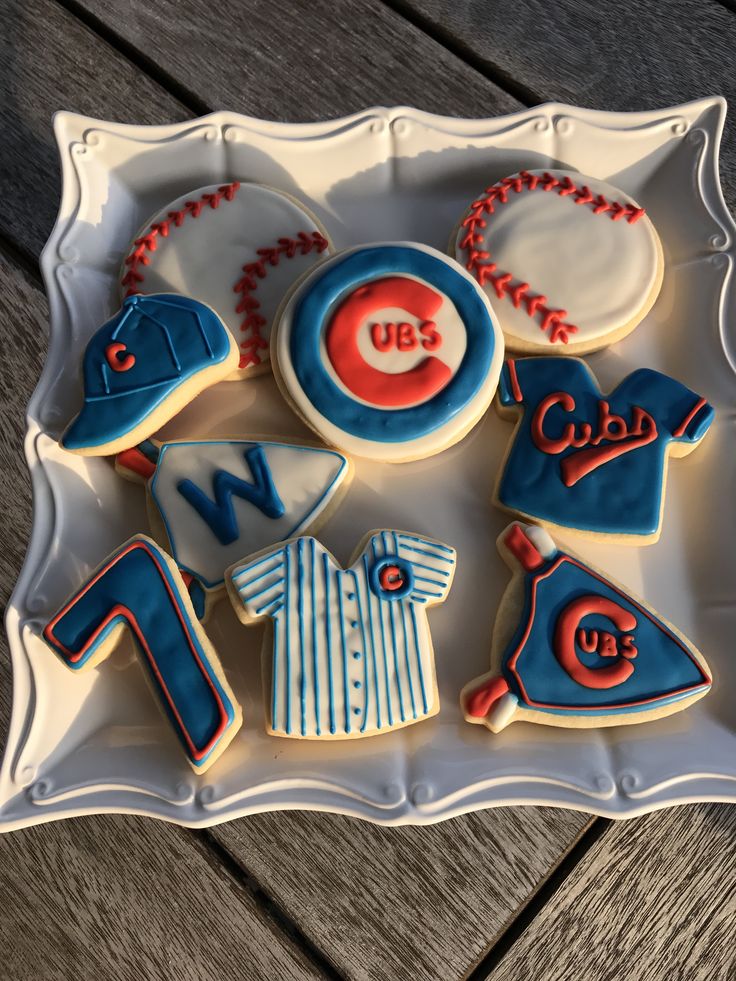 decorated cookies in the shape of shirts and baseballs on a tray with wooden background