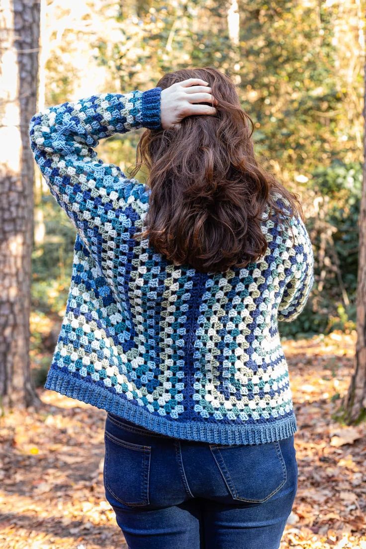 a woman is standing in the woods with her hands on her head and looking back