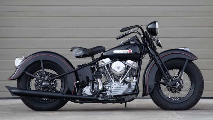 a black motorcycle is parked in front of a garage door and it's side view