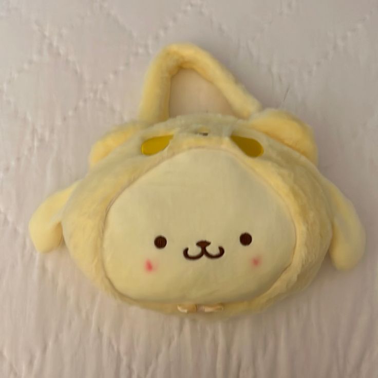 a stuffed animal with a yellow hat on it's head hanging from a wall