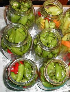 several jars filled with green peppers on top of a table