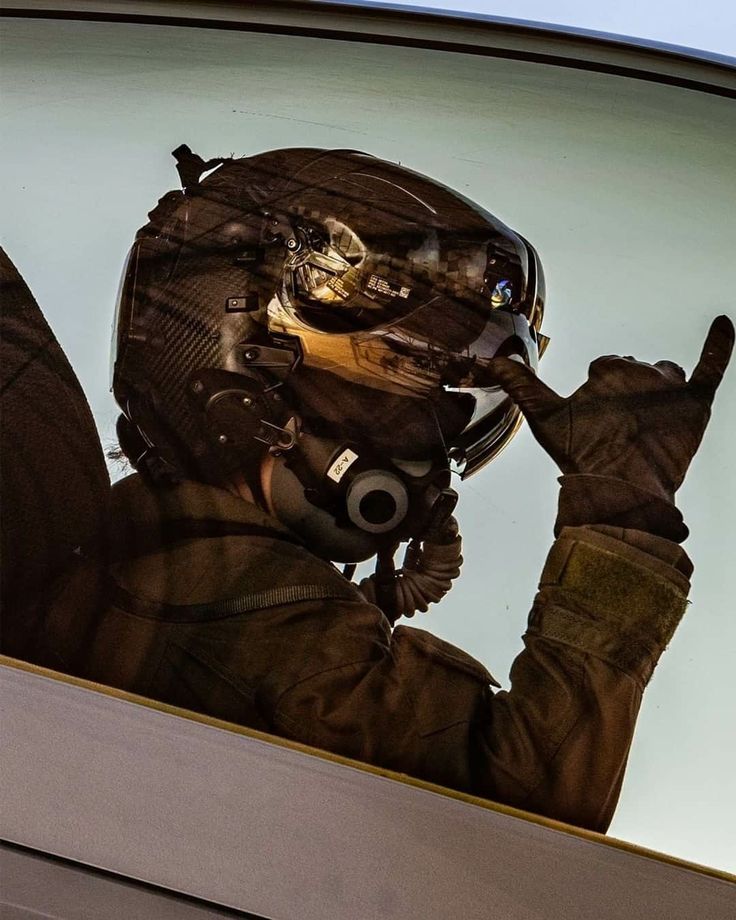 a man in an air force pilot's uniform making the peace sign