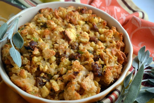 a casserole dish with stuffing and vegetables in it on a table cloth next to an orange napkin