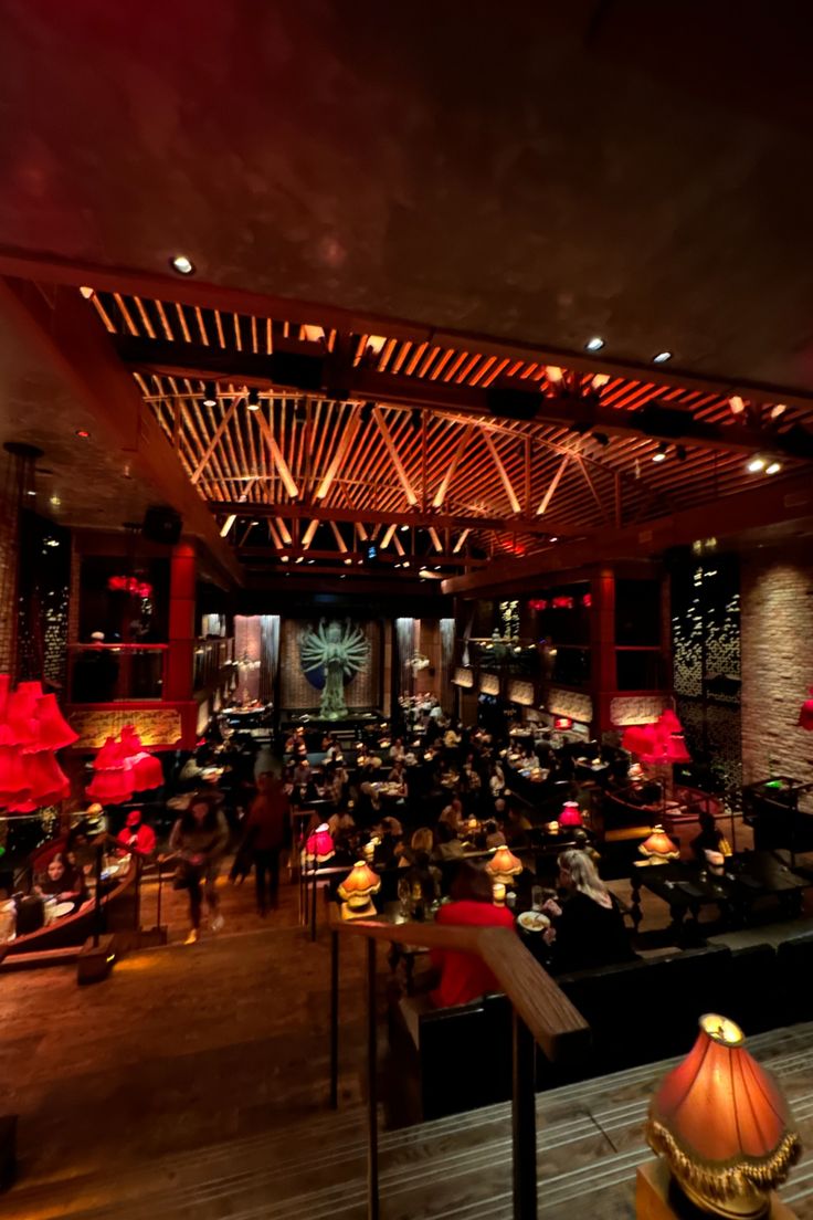 a large room filled with lots of tables and chairs covered in red lights at night