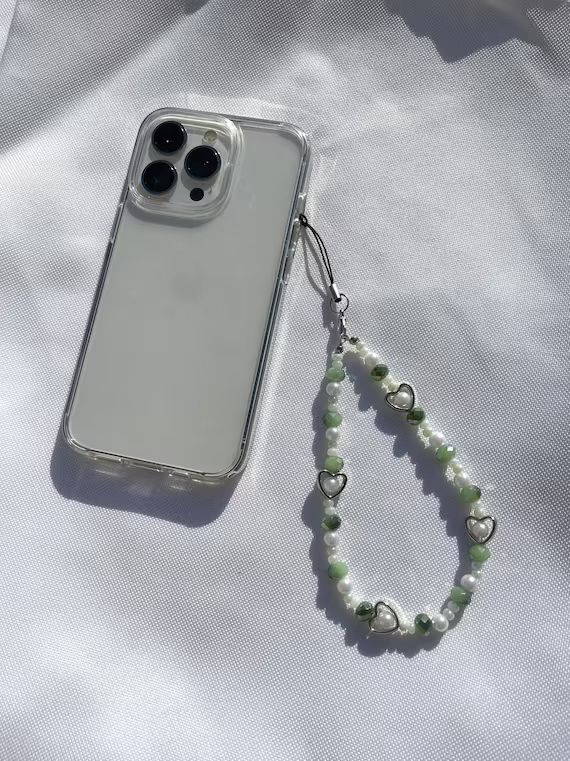 an iphone case with a beaded lanyard attached to it on a white surface