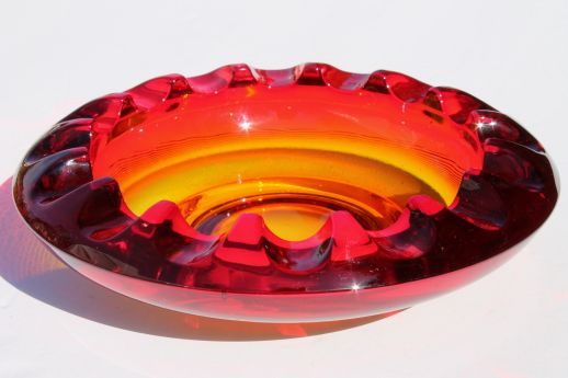 a red glass bowl sitting on top of a white table next to a yellow object