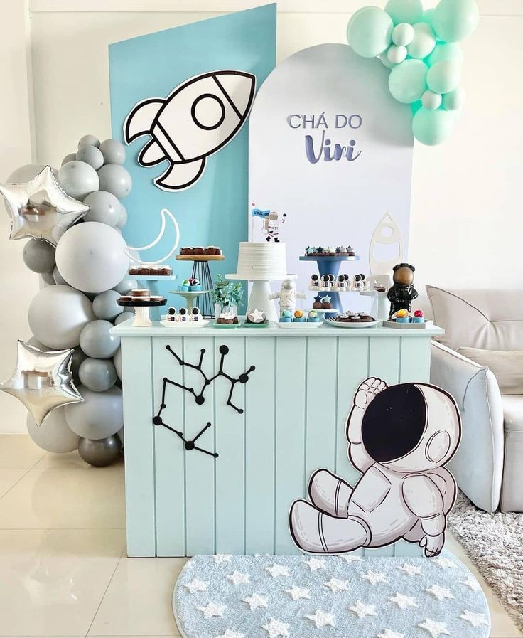 a birthday party with balloons and decorations on the wall, including an astronaut cake stand