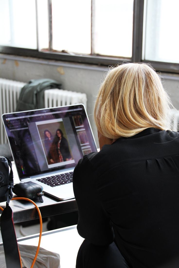 a woman sitting in front of a laptop computer on top of a desk next to a camera