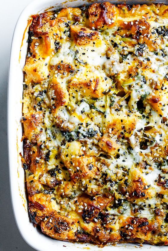 a casserole dish with cheese and spinach in it on a white surface