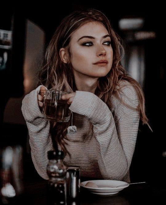 a woman sitting at a table with a glass in her hand