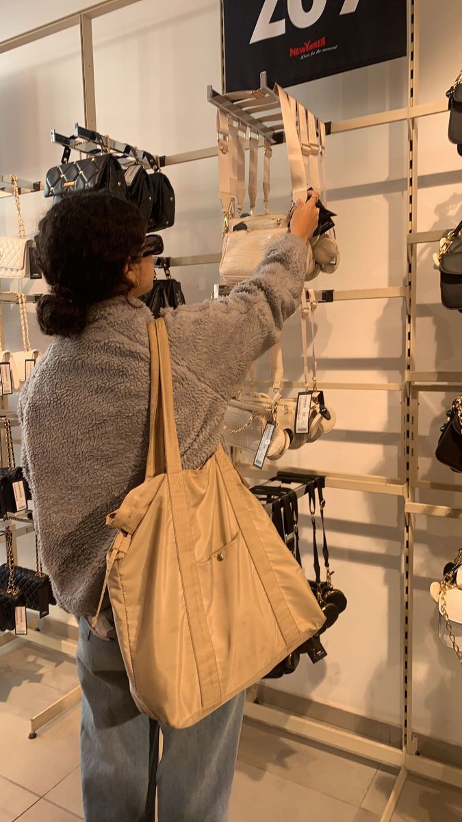 a woman is looking at shoes on display in a shoe store while holding a handbag