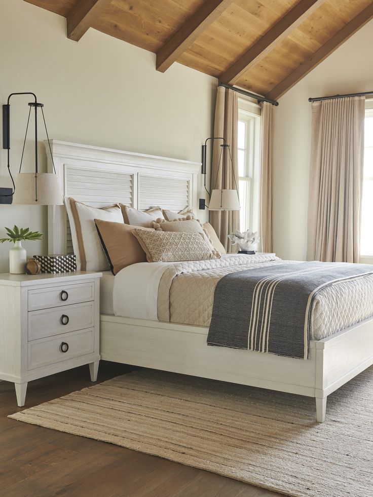 a white bed sitting in a bedroom on top of a wooden floor next to a window