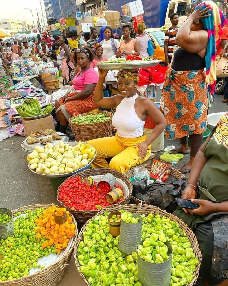 several women sitting in front of baskets filled with fruit and vegetables at an outdoor market