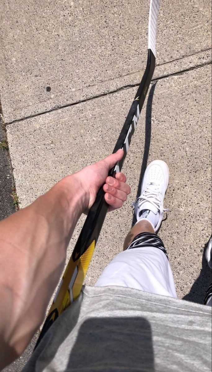 a person holding onto a pair of skis on the sidewalk with their feet propped up