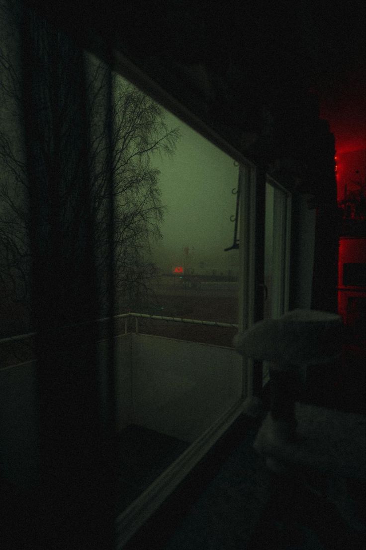 an umbrella is sitting on the window sill in front of a dark room with red lights