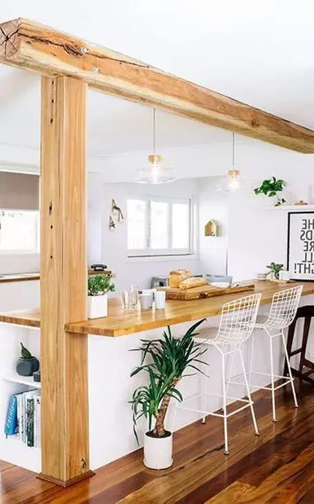 an open concept kitchen and dining area with wood flooring, white walls and wooden beams