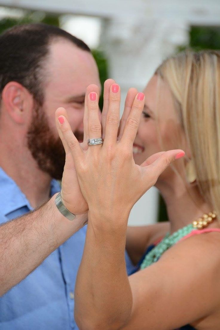 a man and woman holding their hands up to show the ring on their fingers as they stand next to each other