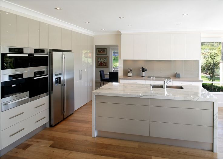 a modern kitchen with white cabinets and stainless steel appliances is featured in this image, there are lemons hanging on the wall