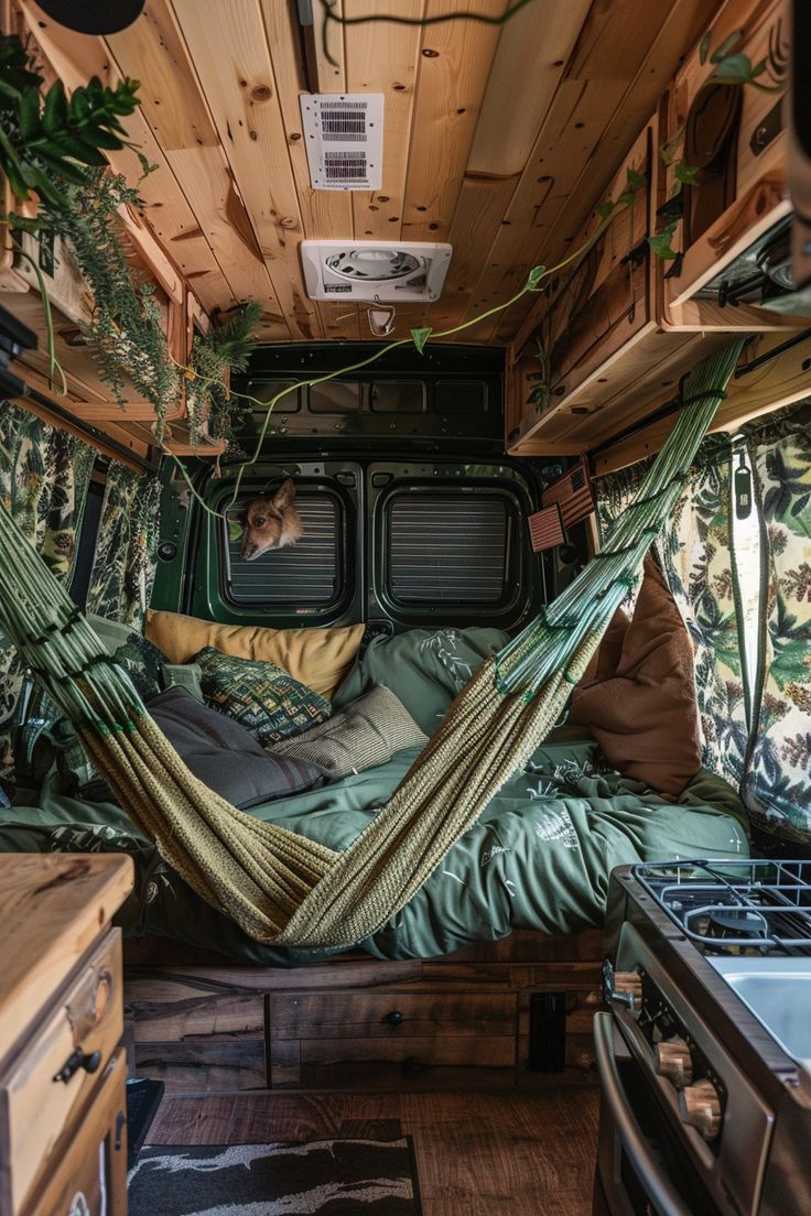 the interior of a camper van with hammock and pillows on it's bed