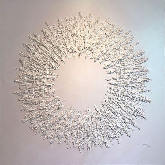 a circular artwork made with silver foil on a white wall