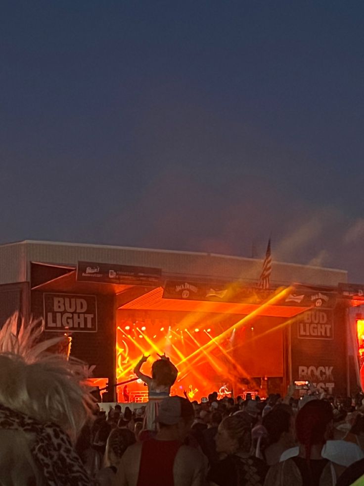 a large group of people standing in front of a stage with lights and sound equipment on it