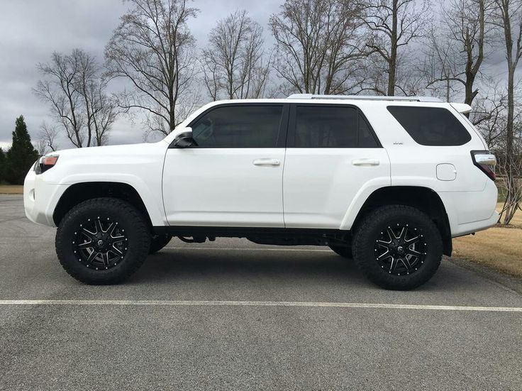 a white toyota 4runner is parked in a parking lot with black wheels and tires