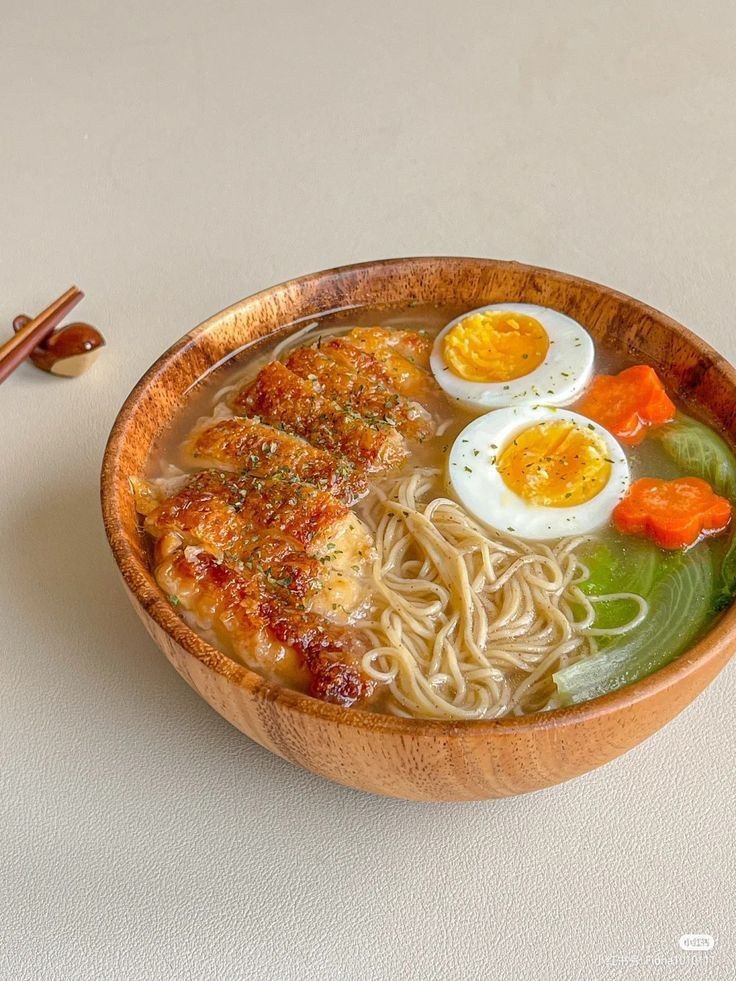 a wooden bowl filled with noodles and meat topped with hard boiled eggs on top of them