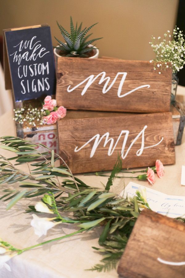 two wooden signs sitting on top of a table next to flowers and succulents