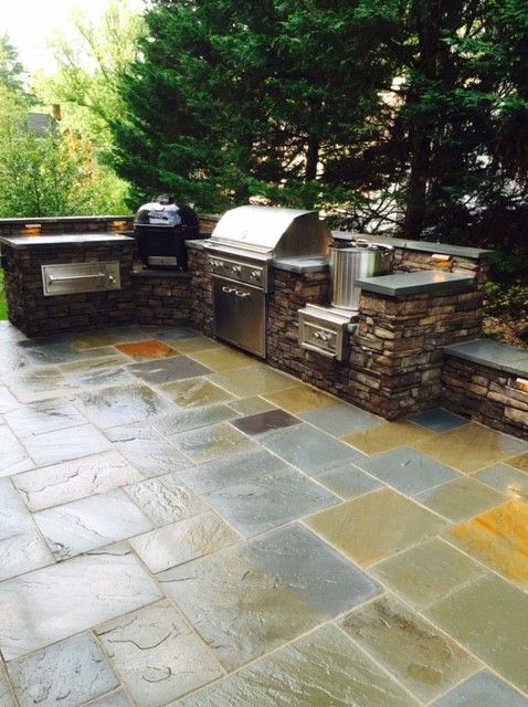 an outdoor kitchen with grills and seating