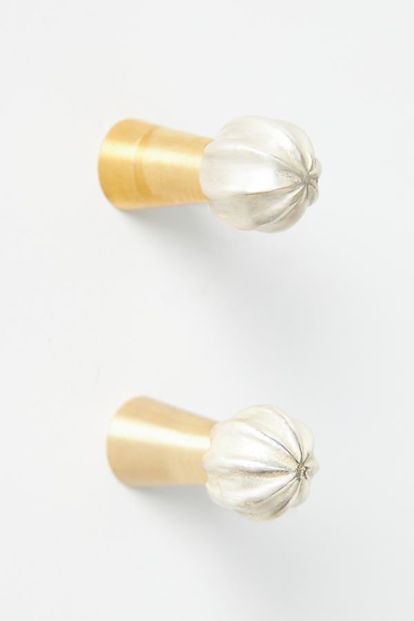 two silver and gold knobs on a white surface, one has a flower in the middle