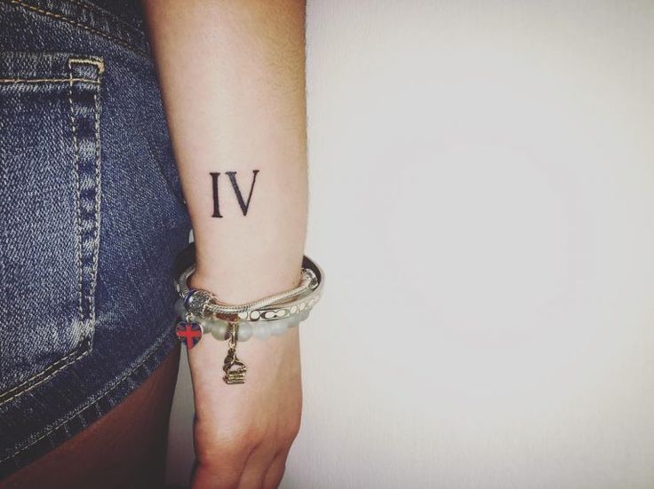 a woman's arm with a small tattoo on it and the word iv written in cursive letters