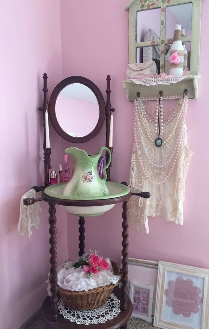 a table with a mirror, vase and other items on it in a pink room