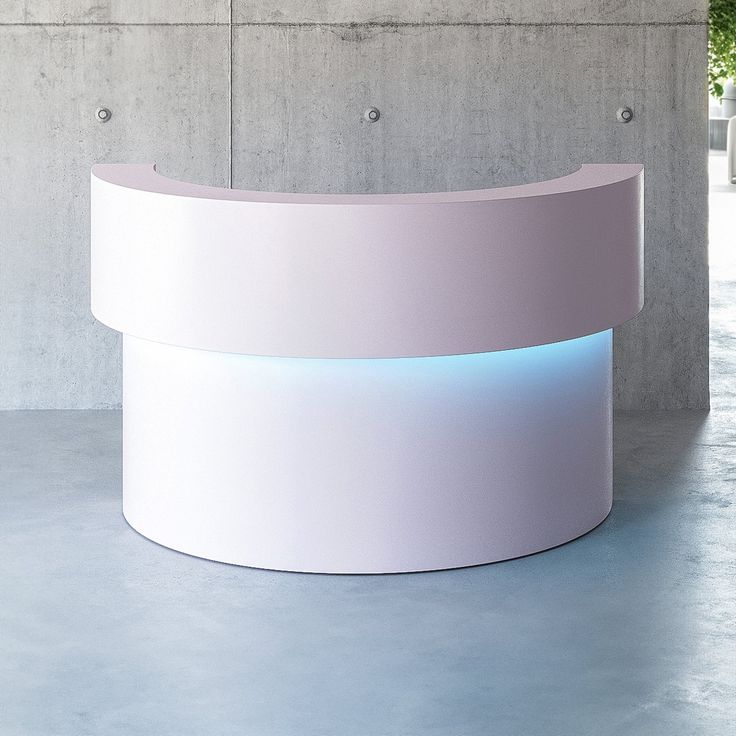 a curved white counter sitting on top of a cement floor