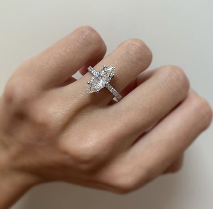 a woman's hand holding an engagement ring with a diamond in the shape of a cross