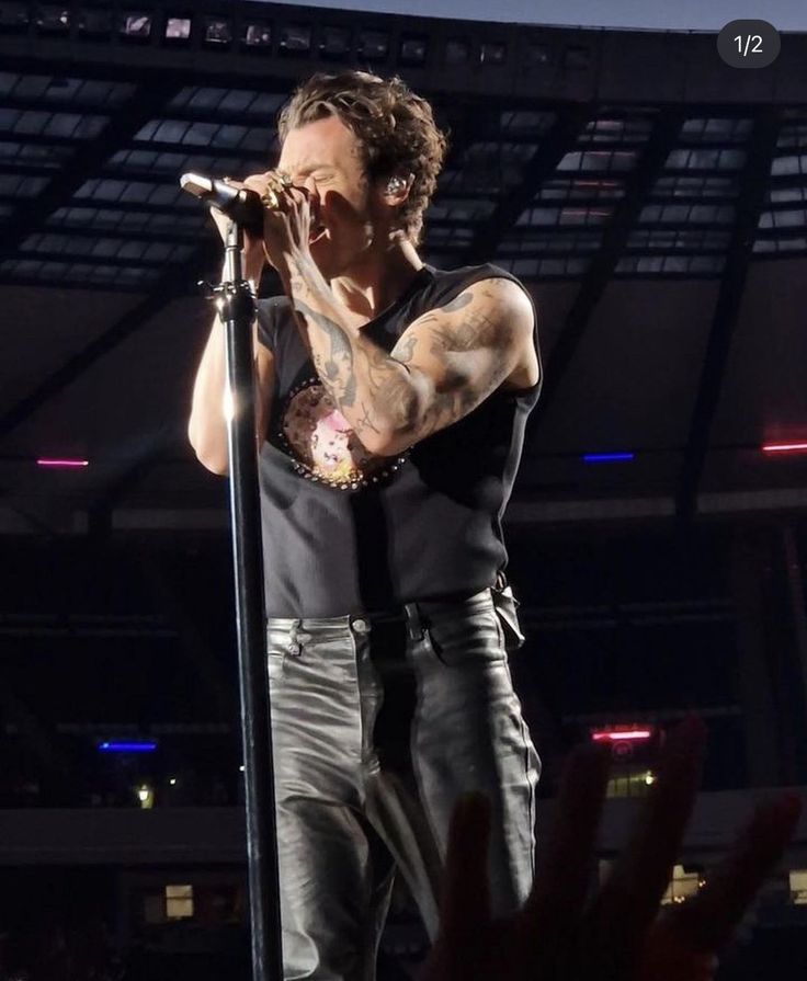 a man standing on top of a stage holding a microphone in his hand and singing