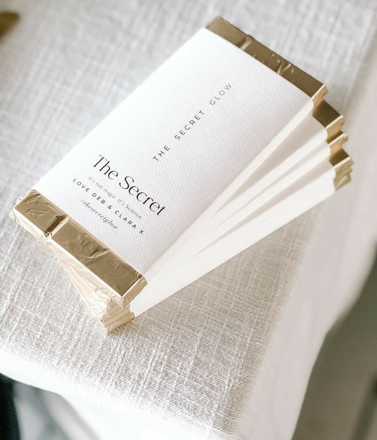 four folded business cards sitting on top of a white cloth covered tablecloth with the words, the secret