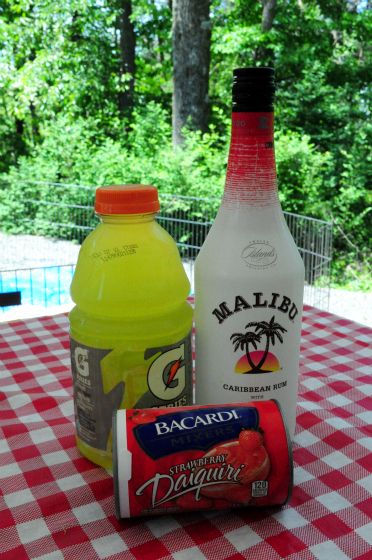 two bottles of juice and one bottle of water sitting on a table with a checkered cloth